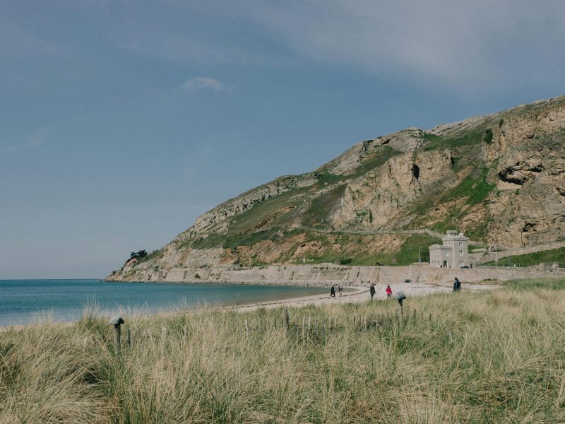 Beautiful view of Llandudno's West Shore Beach with grassy dunes and rocky cliffs in summer.